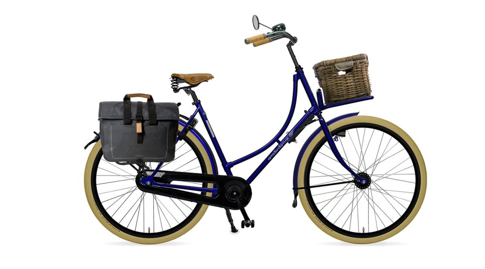 Oma Premium avec cadre bleu nuit, malle en rotin sur le porte-bagage avant et sacoche sur le porte-bagage arrière