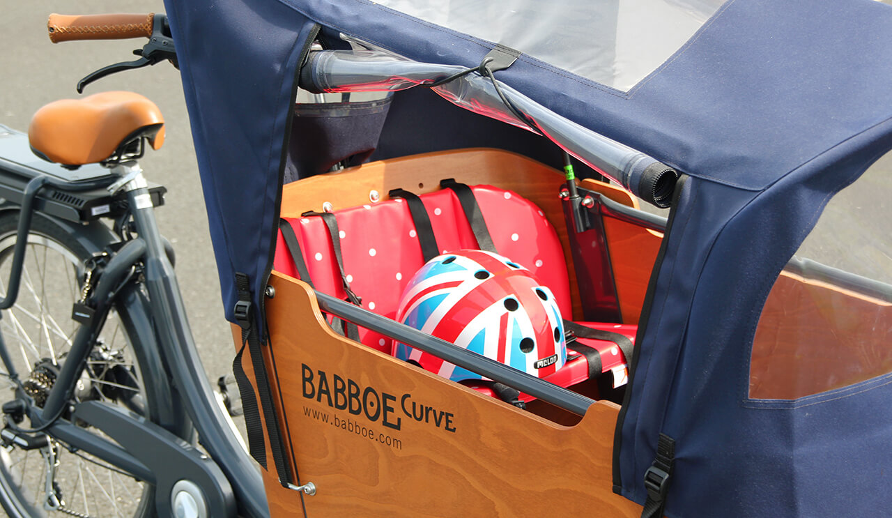 Quelques accessoires indispensables à bord d'un vélo cargo : caque, coussins, protection pluie