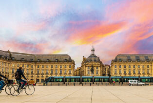 Deux cyclistes à vélo devant la place de la bourse à Bordeaux